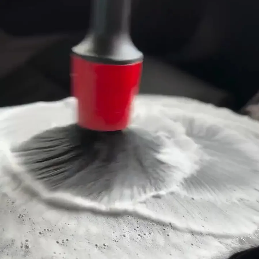 Detailing brush working foam across an interior trim panel